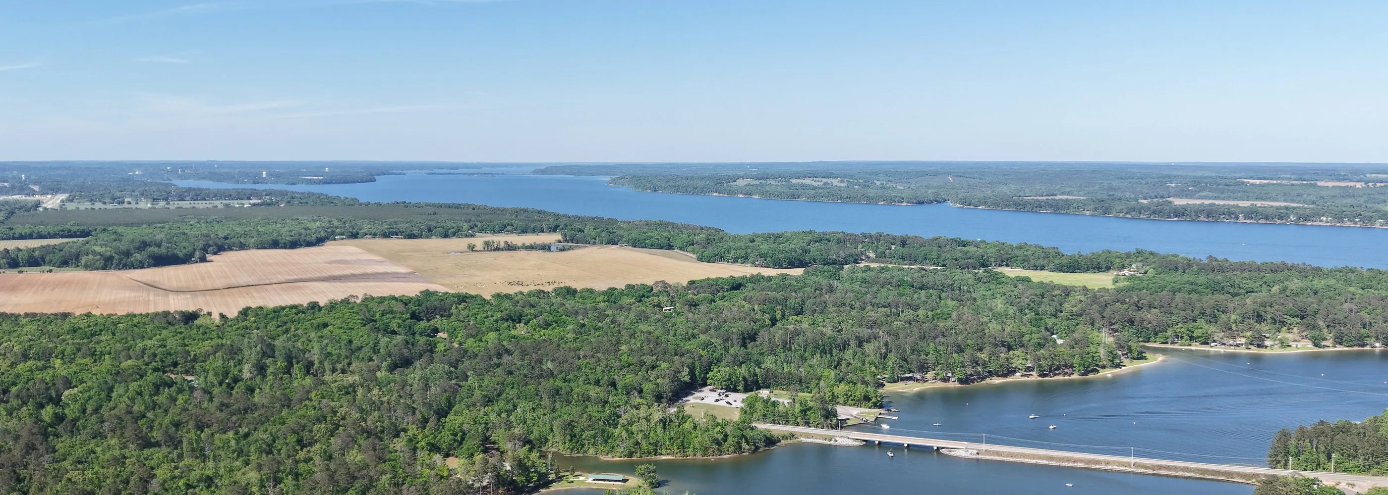 Aerial panorama over Lake Eufaula at 400 feet — the causeway crossing wide blue water between pine shorelines